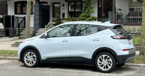 bolt ev parked on a street in front of a house