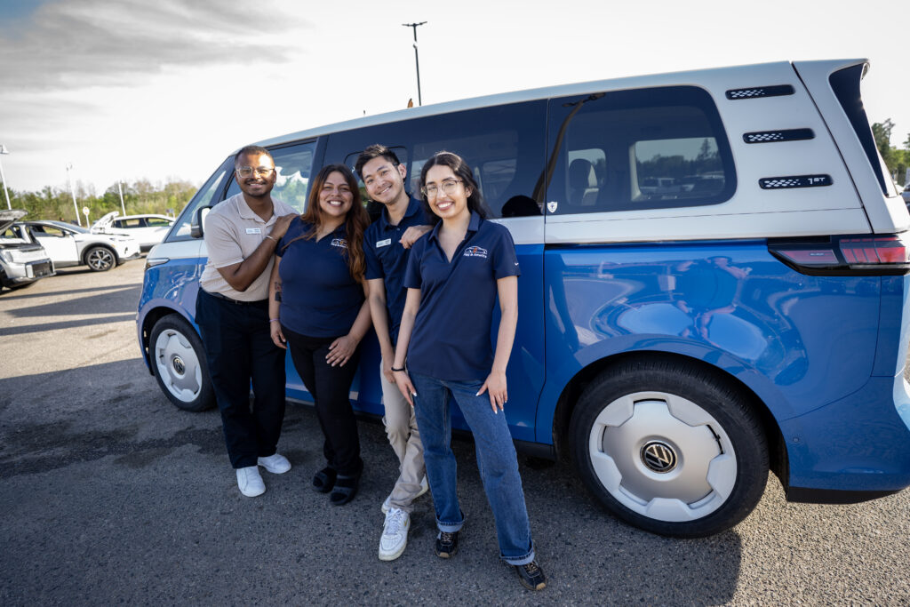 Four Plug In America staff members standing in front of an EV. 